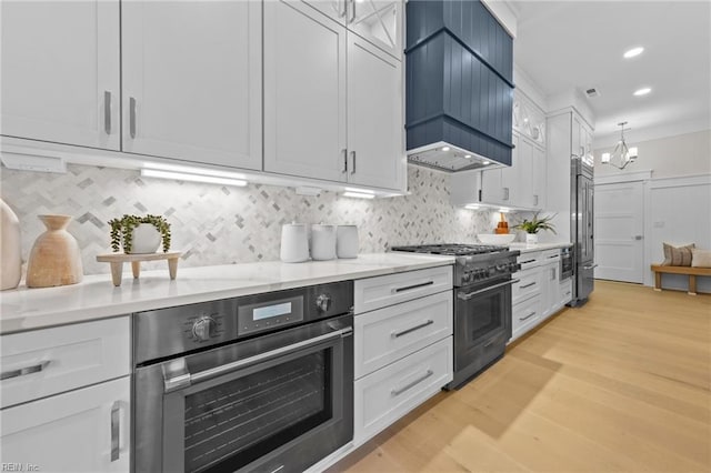 kitchen with high end appliances, premium range hood, and white cabinets