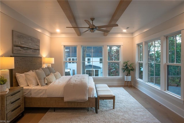 bedroom featuring hardwood / wood-style flooring, beamed ceiling, and ceiling fan