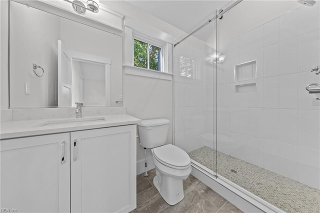 bathroom with toilet, vanity, and a shower with door