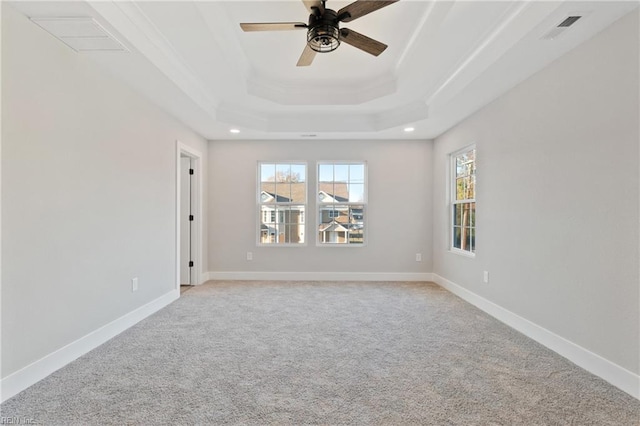 empty room featuring crown molding, light colored carpet, a tray ceiling, and ceiling fan