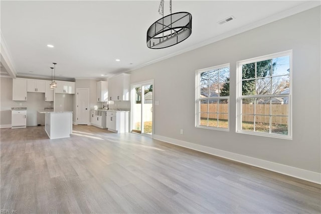 unfurnished living room featuring ornamental molding, sink, and light wood-type flooring