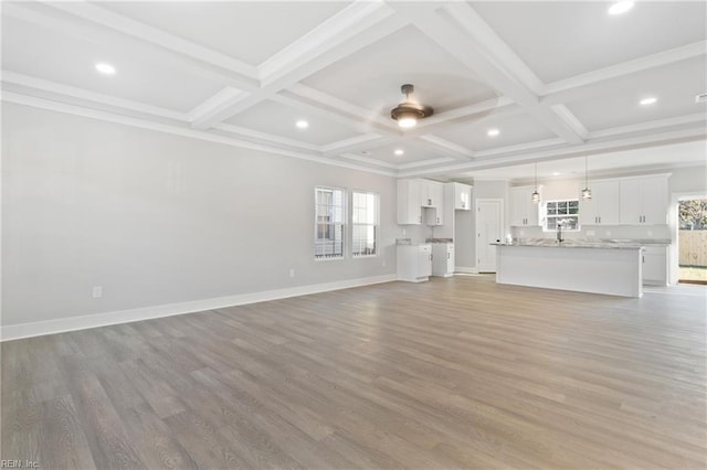 unfurnished living room featuring beam ceiling, wood-type flooring, and plenty of natural light