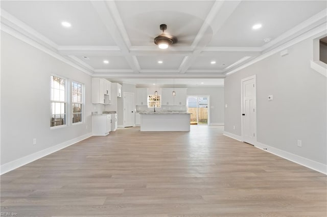 unfurnished living room featuring light wood-type flooring, coffered ceiling, and plenty of natural light