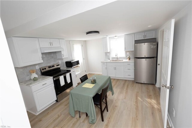 kitchen with white cabinetry, tasteful backsplash, stainless steel appliances, and light wood-type flooring