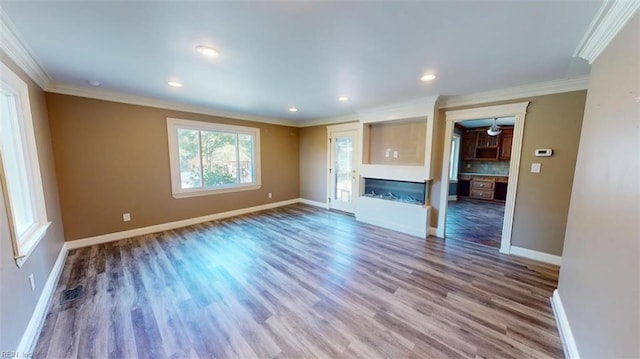 unfurnished living room with wood-type flooring and ornamental molding