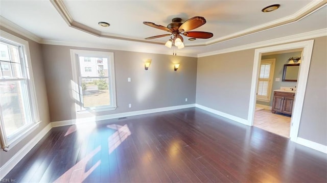 unfurnished room with ornamental molding, ceiling fan, dark wood-type flooring, and a raised ceiling