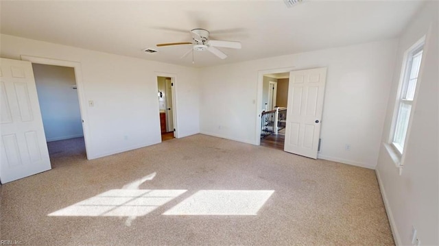 unfurnished bedroom featuring connected bathroom, light carpet, and ceiling fan