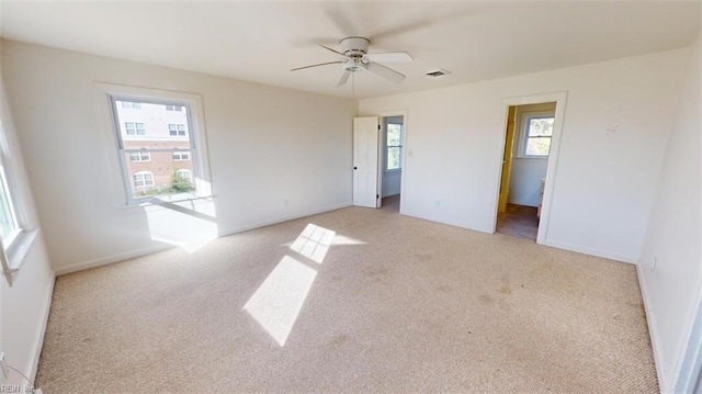 carpeted spare room featuring ceiling fan and a healthy amount of sunlight