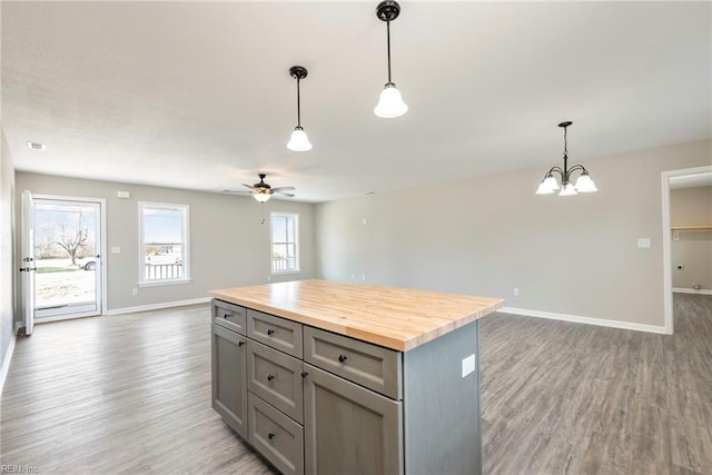 kitchen with hanging light fixtures, gray cabinetry, hardwood / wood-style floors, a center island, and butcher block countertops