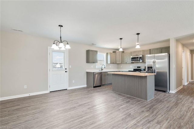 kitchen with a center island, appliances with stainless steel finishes, gray cabinetry, and wood-type flooring