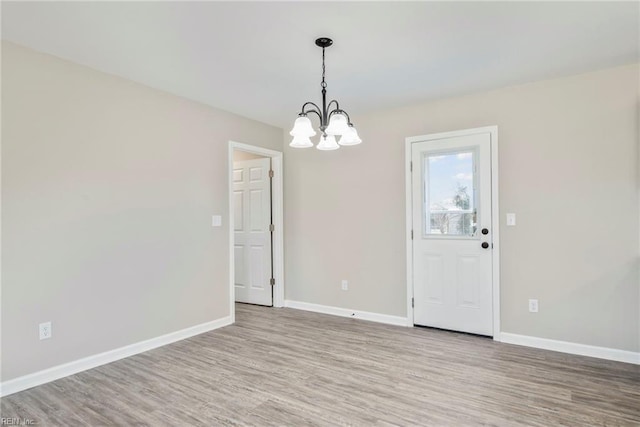 unfurnished dining area featuring hardwood / wood-style flooring and an inviting chandelier