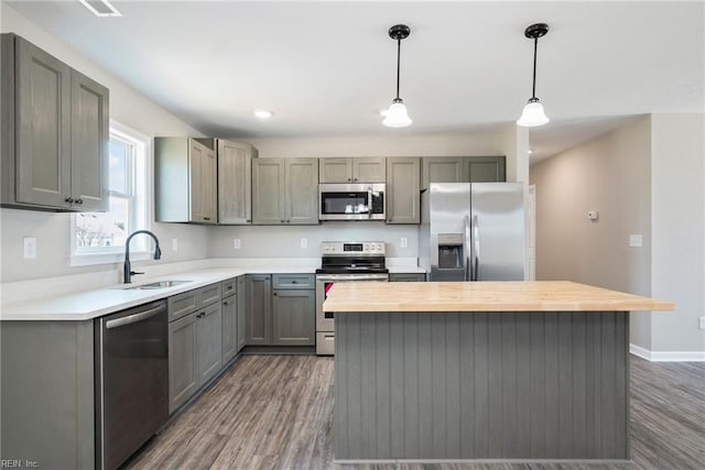 kitchen featuring appliances with stainless steel finishes, decorative light fixtures, sink, and gray cabinetry