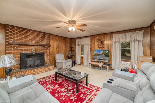 living room with a wood stove, carpet, wood walls, and ceiling fan