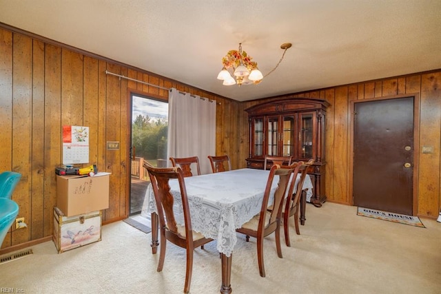 dining room with wood walls, light carpet, and an inviting chandelier