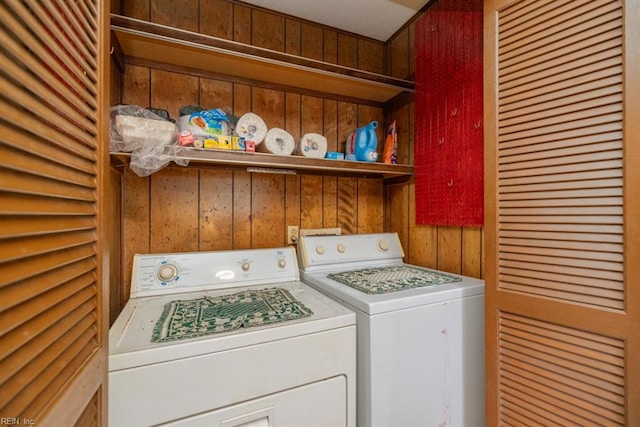 washroom featuring washer and clothes dryer and wooden walls