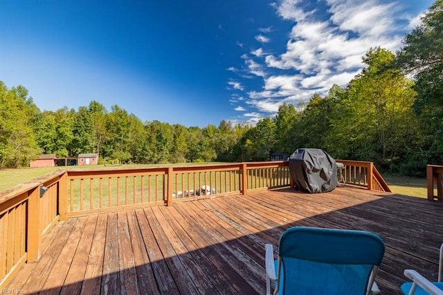 deck featuring grilling area, a storage unit, and a yard