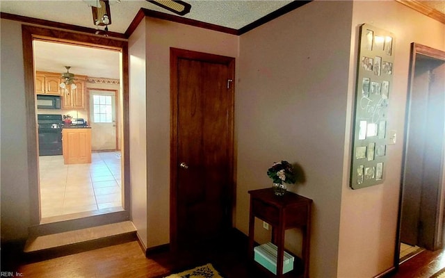 hall with hardwood / wood-style floors, ornamental molding, and a textured ceiling