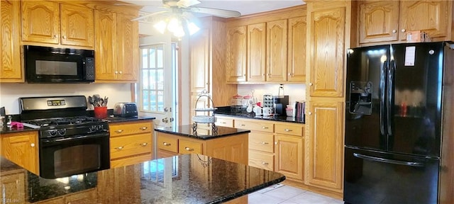 kitchen with ceiling fan, black appliances, a center island, and dark stone counters