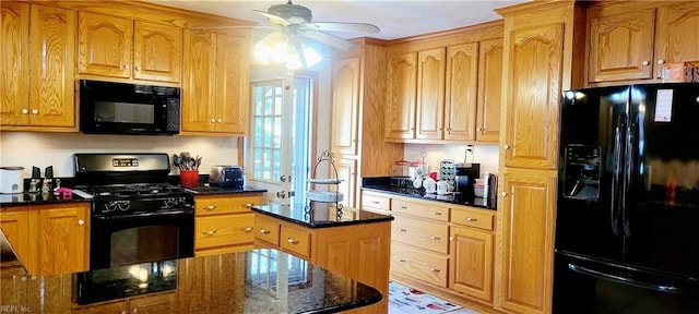 kitchen with black appliances, dark stone counters, ceiling fan, and a kitchen island