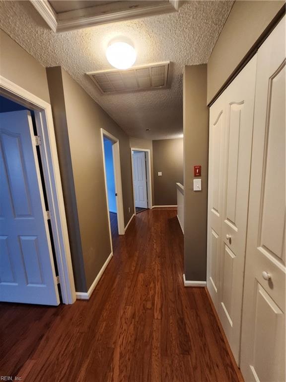 hall with a textured ceiling and dark hardwood / wood-style floors