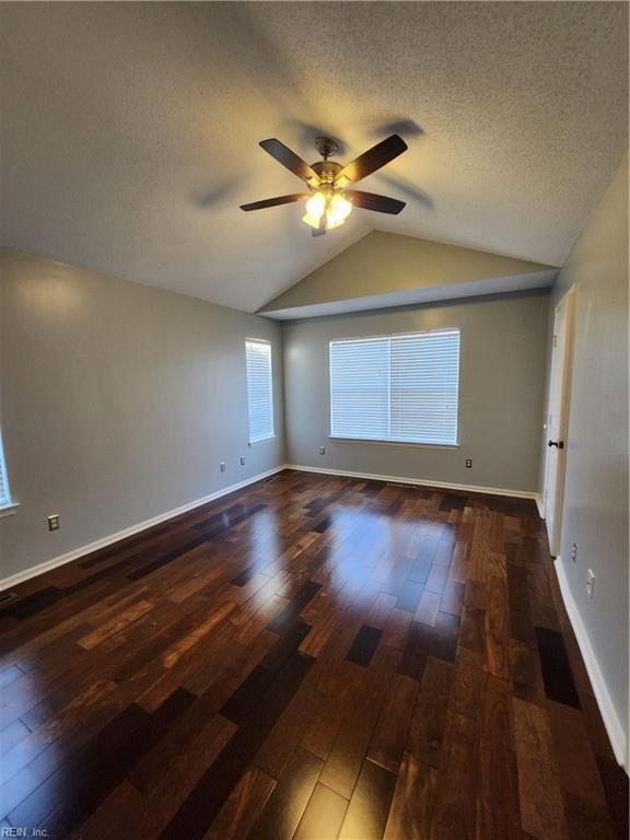 empty room featuring lofted ceiling, a textured ceiling, dark hardwood / wood-style floors, and ceiling fan