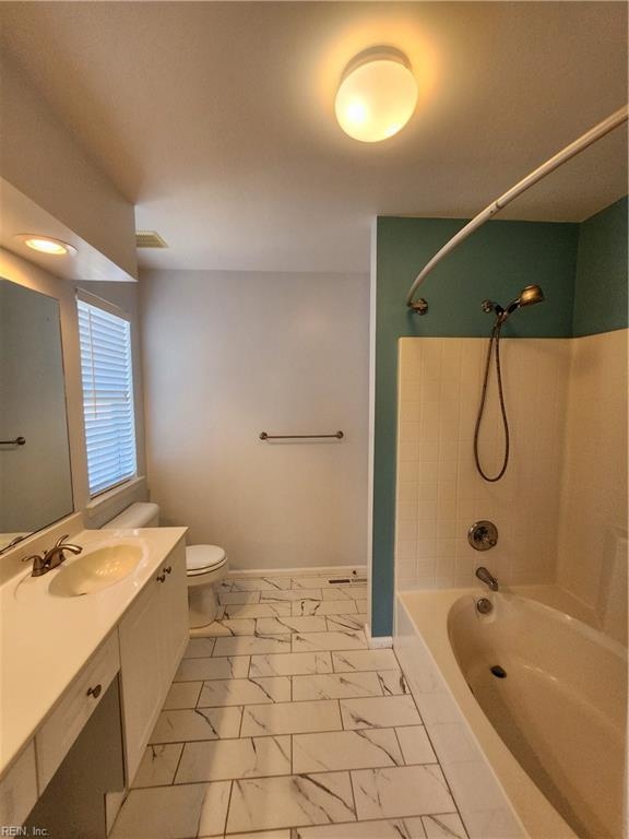 full bathroom featuring toilet, tiled shower / bath, and vanity