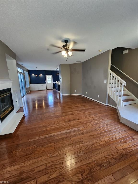 unfurnished living room featuring a textured ceiling, dark hardwood / wood-style floors, and ceiling fan