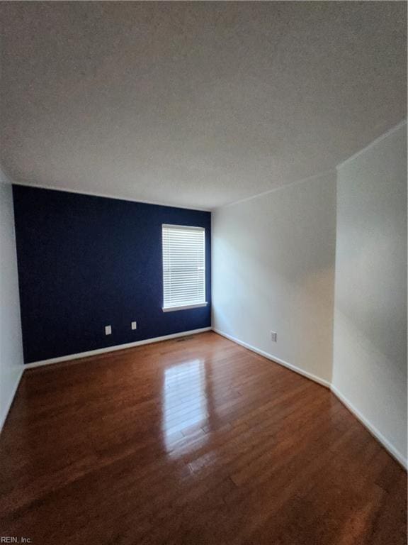 empty room featuring hardwood / wood-style floors, a textured ceiling, and vaulted ceiling