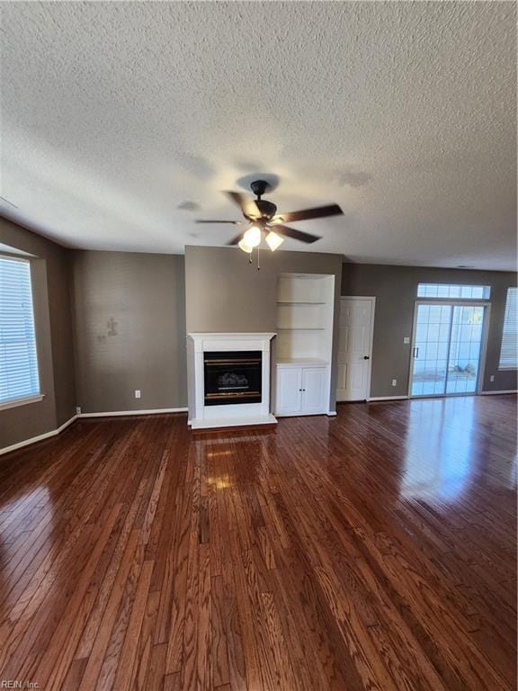 unfurnished living room featuring ceiling fan, a textured ceiling, and dark hardwood / wood-style flooring