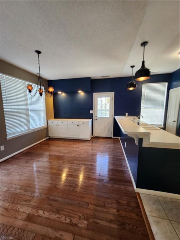 kitchen with an inviting chandelier, a breakfast bar, pendant lighting, and dark hardwood / wood-style flooring