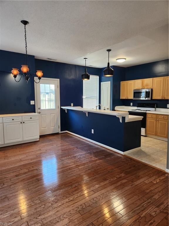 kitchen featuring a kitchen breakfast bar, light hardwood / wood-style flooring, white electric range oven, and hanging light fixtures