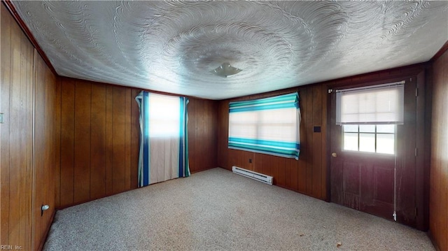 carpeted entryway featuring wood walls, a textured ceiling, and a baseboard radiator