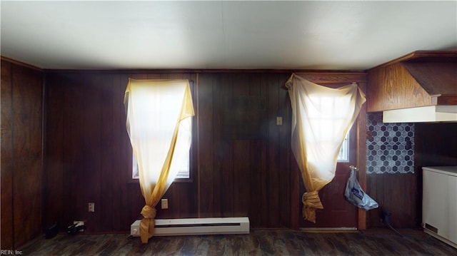 interior space with washer / dryer, a baseboard radiator, dark wood-type flooring, and wood walls