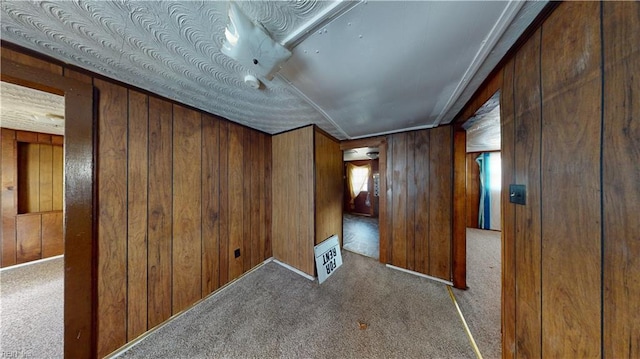 carpeted empty room featuring wooden walls