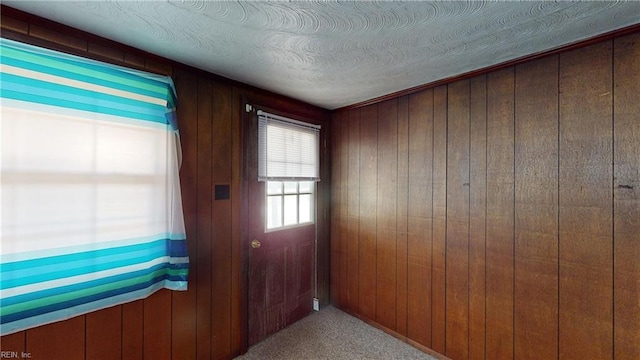 doorway to outside with wood walls and a textured ceiling