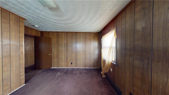 unfurnished bedroom with dark carpet and wooden walls