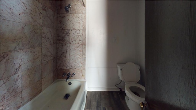 bathroom featuring hardwood / wood-style floors, tiled shower / bath combo, and toilet