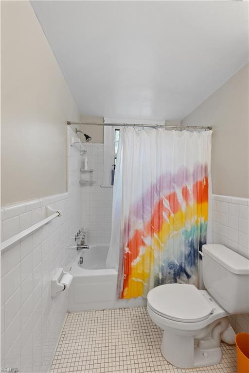 bathroom with tile walls, shower / bath combination with curtain, toilet, and tile patterned floors