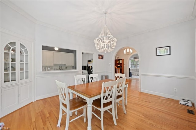 dining room featuring ornamental molding, light hardwood / wood-style flooring, and a chandelier