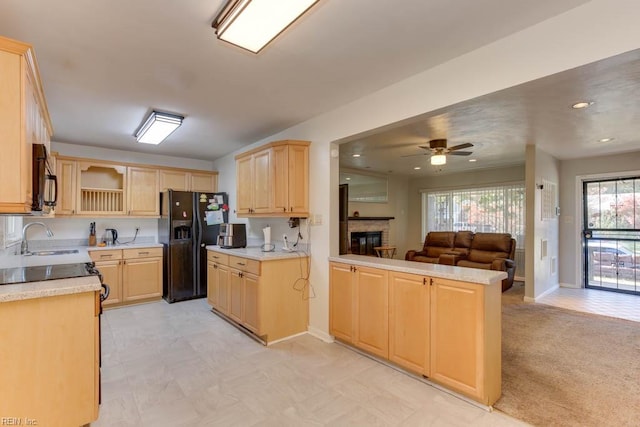 kitchen featuring a brick fireplace, black appliances, kitchen peninsula, and a wealth of natural light