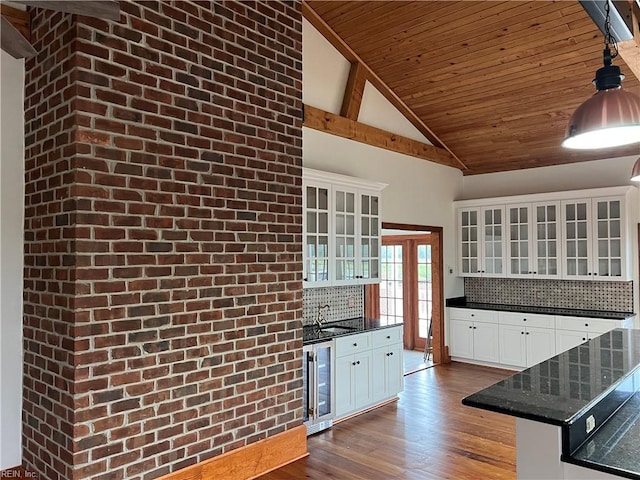 kitchen featuring dark stone counters, backsplash, hanging light fixtures, white cabinets, and beverage cooler