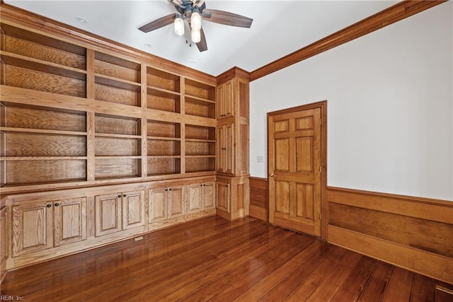 empty room featuring wood walls, ceiling fan, crown molding, and dark hardwood / wood-style flooring