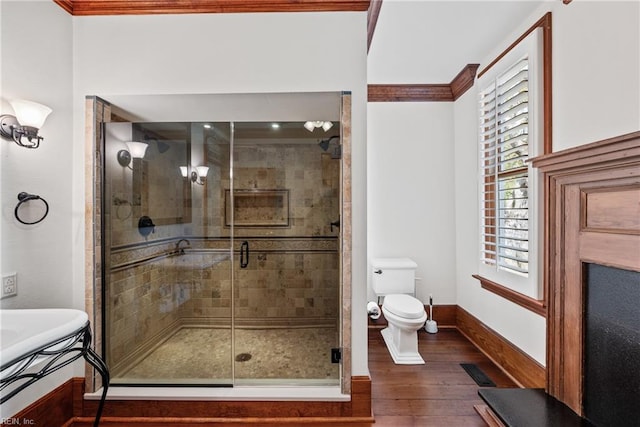 bathroom featuring hardwood / wood-style floors, a shower with door, toilet, and crown molding