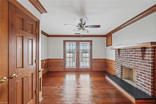 unfurnished living room with a brick fireplace, dark wood-type flooring, ceiling fan, and crown molding