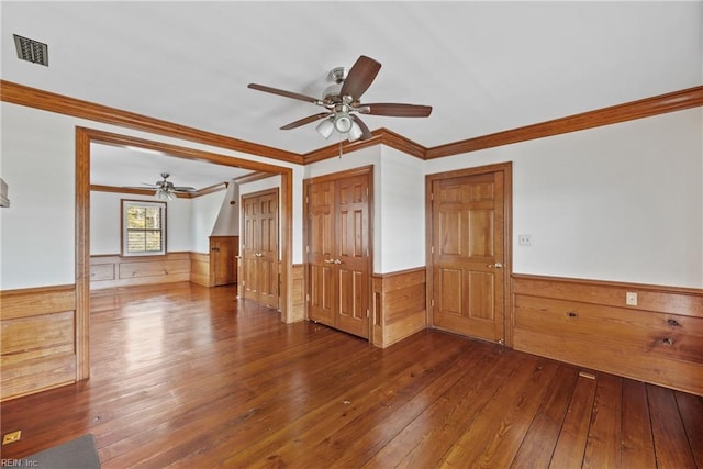 empty room featuring dark wood-type flooring, ceiling fan, and crown molding