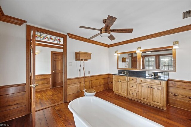 bathroom featuring a bath, wood-type flooring, crown molding, vanity, and ceiling fan