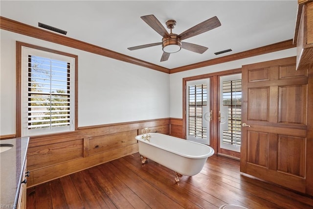 interior space with a bathing tub, wood-type flooring, ornamental molding, and ceiling fan