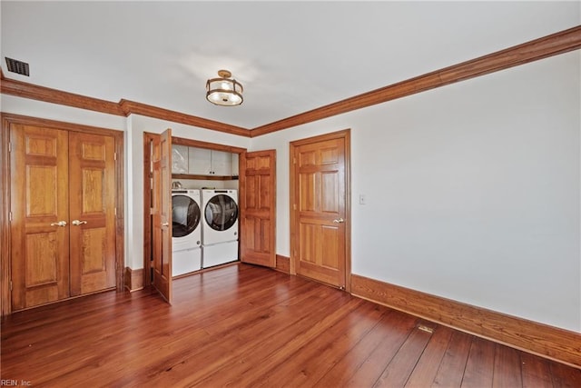 laundry area featuring wood-type flooring, separate washer and dryer, and crown molding