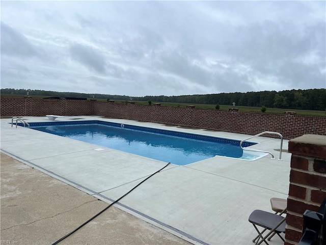 view of swimming pool with a diving board and a patio