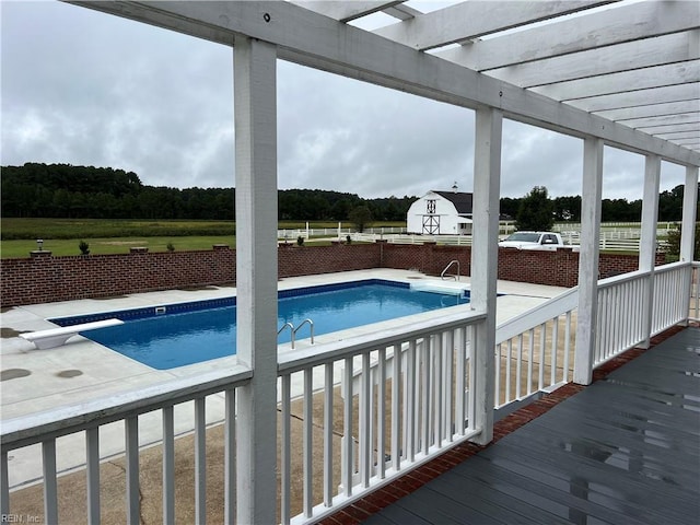 view of swimming pool featuring a diving board, a deck, a pergola, and a patio area